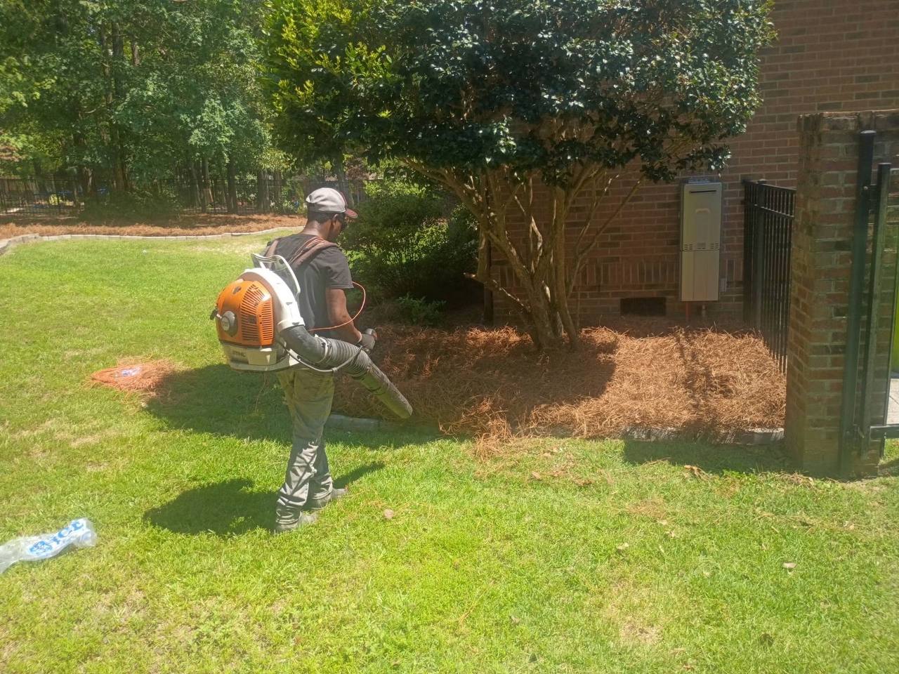 Crew member with backpack blower finishing a bed